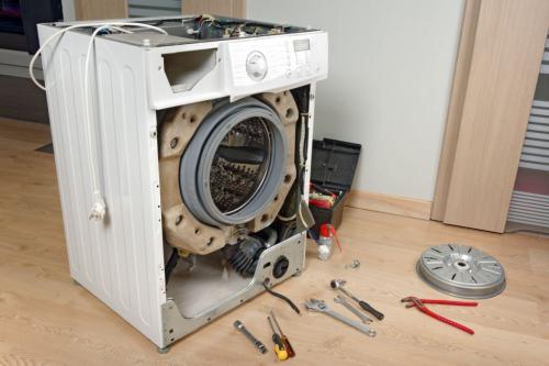 A service technician repairs a damaged washing machine